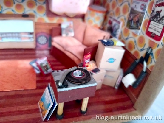 record player, bike fork loo roll holder, sofa, magazine, boxes with snacks on top