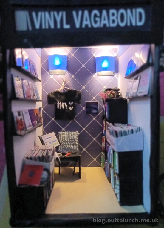 the finished shop. the shelves are full. display shelves show a selection of sleeves. a tshirt hangs on the wall.